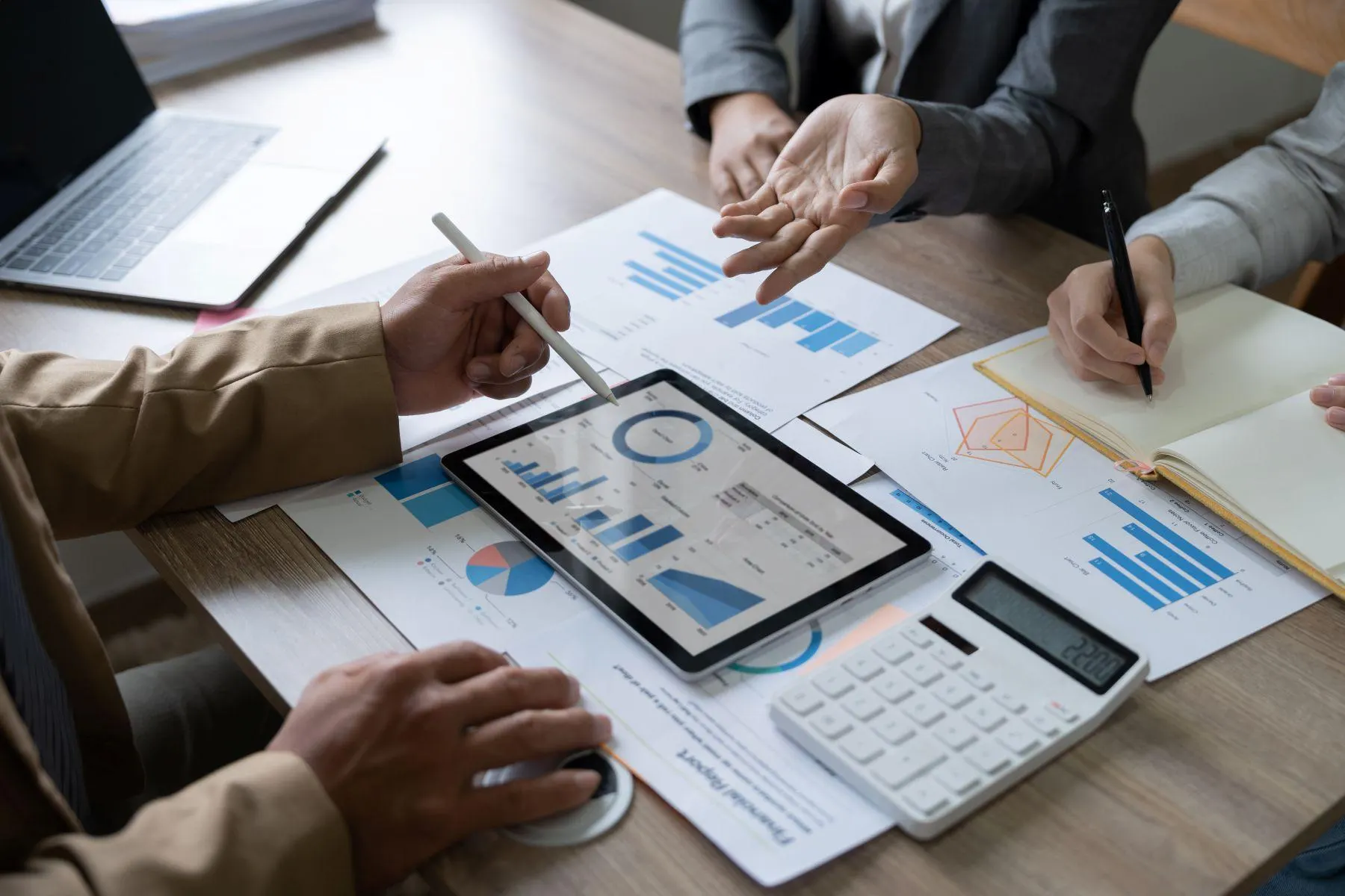 Team-analyzing-financial-data-on-a-tablet-and-discussing-reports-at-a-meeting.webp